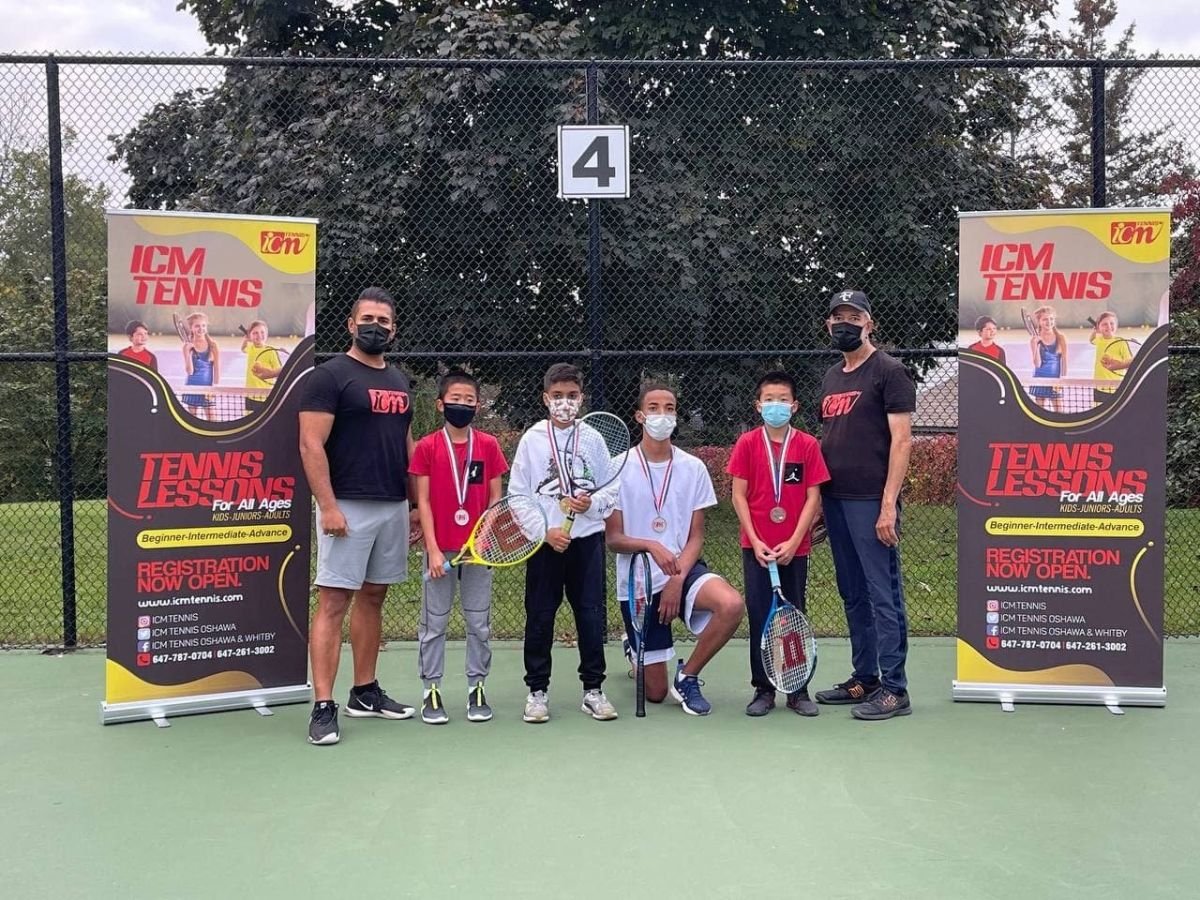 Two coaches and four players with medals between two ICM banners on an outdoor court.