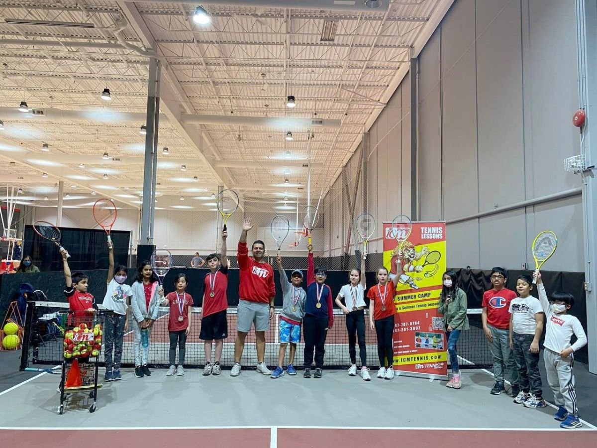 Players raising their racquets at the net in the indoor facility in Whitby after the 12-and-under tournament.