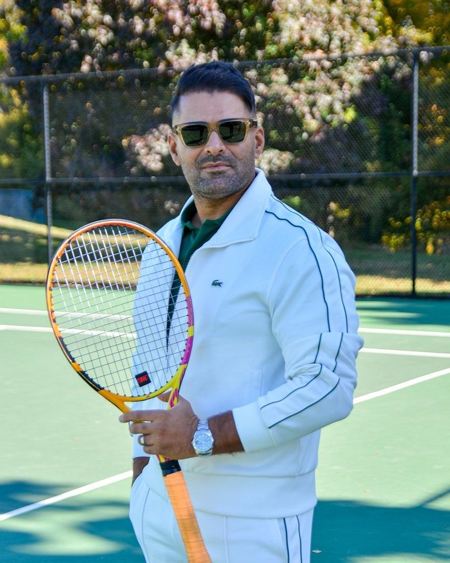 Mahdi Taheri, director of ICM Tennis, on an outdoor court holding a racquet.