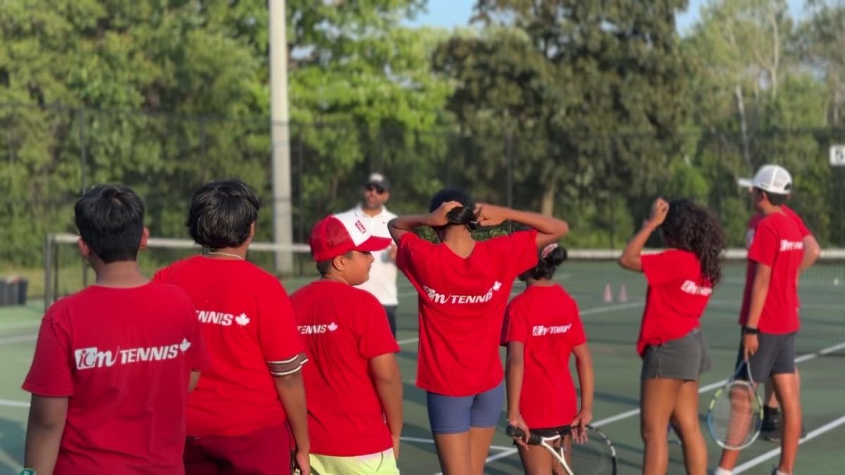 ICM juniors in red shirts gather around their coach before a drill.